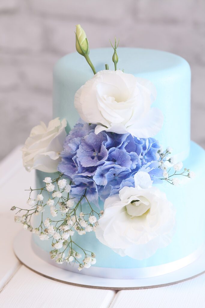 Błękitny tort zimowy z białymi kwiatami.