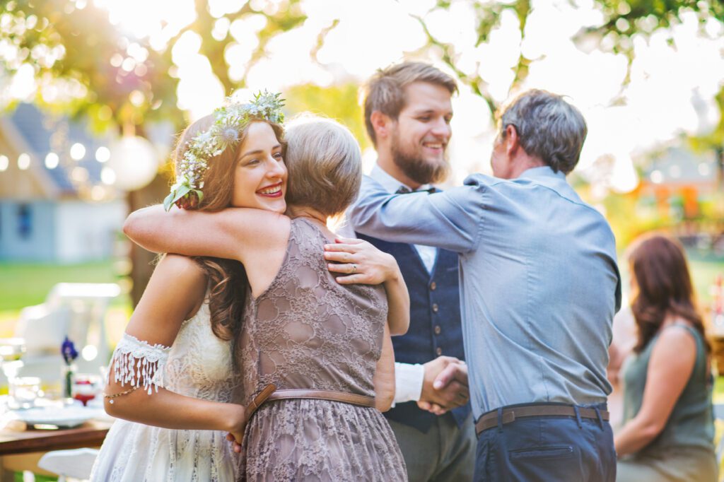 Młodzi kontra rodzice - Para Młoda przytula się na weselu z rodzicami.