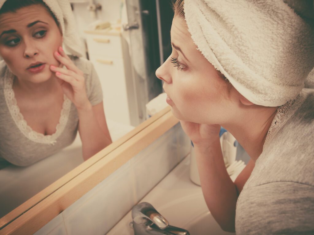 kobieta ogląda swoją twarz w lustrze