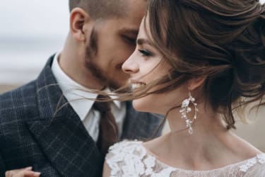 Elegancka para młoda na plaży, romantyczna fotografia ślubna, panna młoda z ozdobnymi kolczykami, naturalna uroda i miłość.