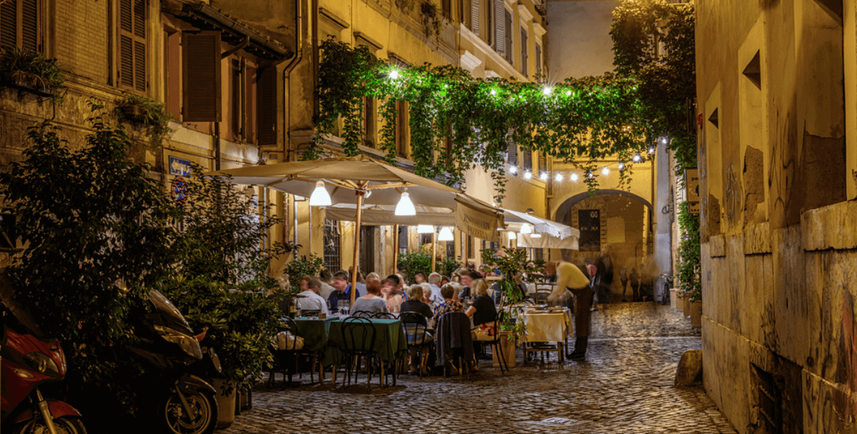 Włochy, wieczór, uliczka i restauracja ze stolikami na zewnątrz wypełniona ludźmi
