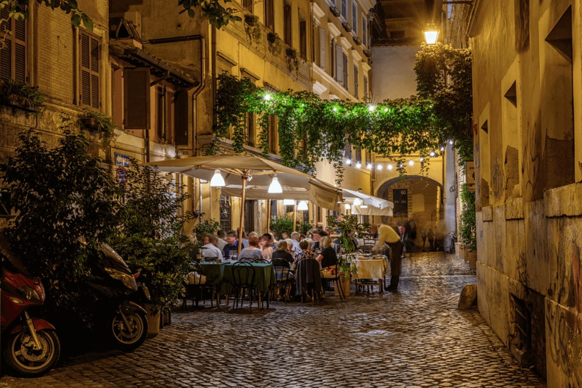 Włochy, wieczór, uliczka i restauracja ze stolikami na zewnątrz wypełniona ludźmi