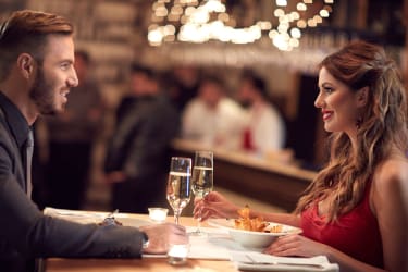 Para na romantycznej kolacji w eleganckiej restauracji, kieliszki z winem, atmosfera miłości.