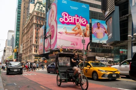 Ulica Nowego Jorku z billboardem filmu Barbie, żółtą taksówką i rikszą na Times Square.