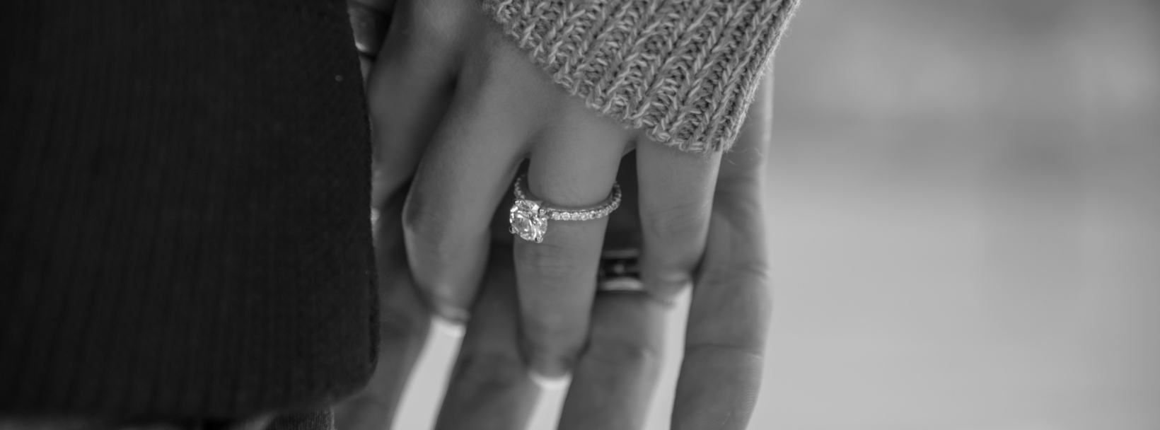 kobieta demonstruje na której ręce nosi się pierścionek zaręczynowy trzymając dłoń partnera