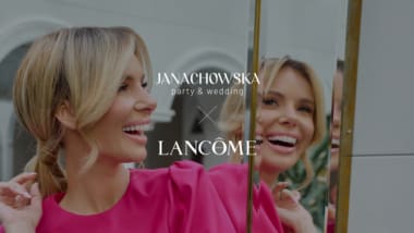 Uśmiechnięta kobieta w różowej sukience przed lustrem, logo Janachowska party & wedding oraz Lancôme